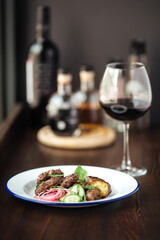 Mini beef cutlets with potato and cucumbers and a glass of red wine
