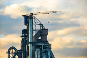 Cement plant with high factory structure and tower crane at industrial production area.