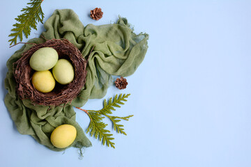 Painted Easter eggs on a green napkin on a blue background, top view. Layout, copy space