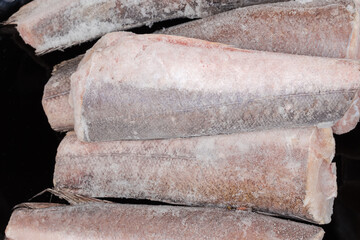Top view of frozen Argentine hake carcasses on black plate