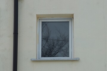 Fototapeta premium one white small window on the gray concrete wall of the building