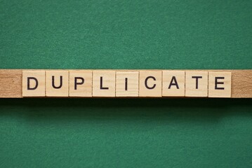 gray word duplicate made of wooden square letters on green background