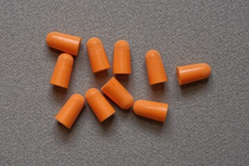 heap of red plastic earplugs on a gray table
