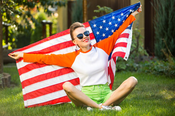 american football fan concept. Woman with american flag sitting on green lawn