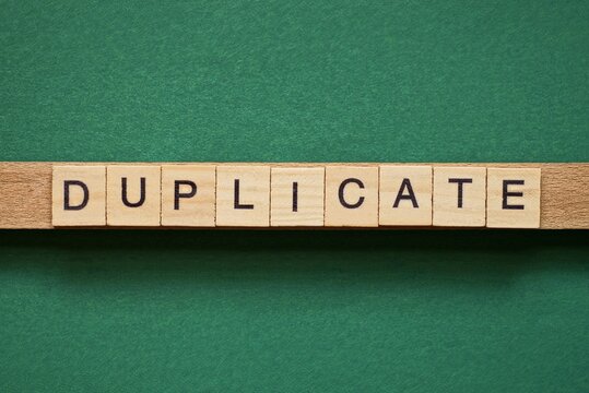 gray word duplicate made of wooden square letters on green background