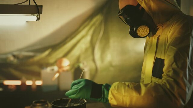 Illegal chemist cooks drugs in underground laboratory wearing mask and works with toxic chemical compounds
