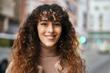 Fototapeta premium Young hispanic woman smiling happy standing at the city