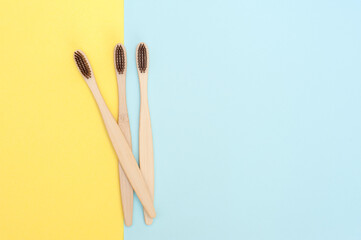 Bamboo toothbrush on a yellow and blue background. Copy space