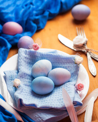 Obraz na płótnie Canvas Blue Easter eggs in a white plate, on a natural wooden table.