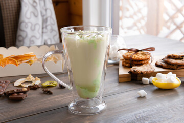 A mug of marshmallow drink on the table by the window.