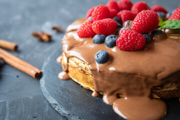 Pancakes with dessert filling and berries on a dark background.