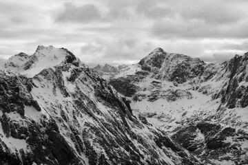 Raues Gebirge mit steilen Flanken und Schnee auf den Lofoten, Norwegen an einem bewölkten Tag