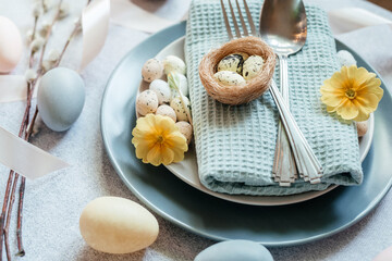 Minimal Easter flatlay with festive Easter tableware, Easter eggs, willow catkin branches, bird's nest