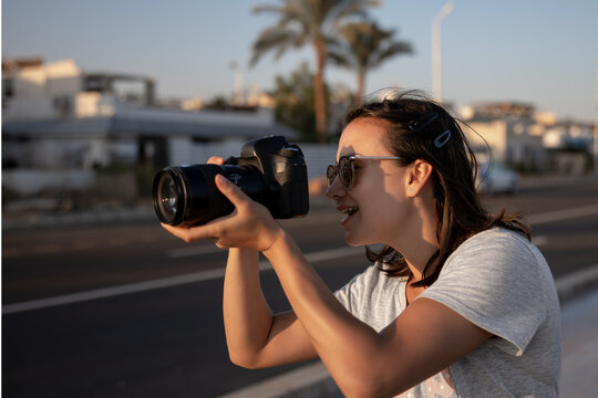 A young girl in sunglasses with a professional camera makes a photo.