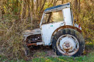 Fototapeta na wymiar Vieux tracteur abandonné dans la campagne en lisière d'un bois
