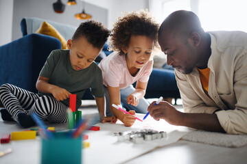 Father with two small children drawing pictures at home, multi ethnic family and home schooling.