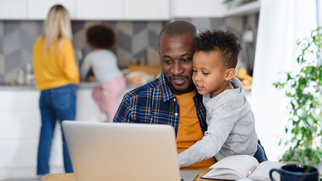 Man with wife and children using laptop, working in home office. - Powered by Adobe