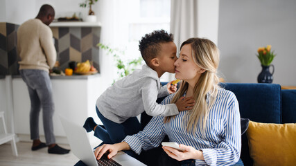 Mother with son and husband using laptop, working in home office.