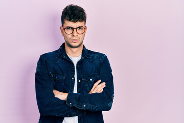 Fototapeta premium Young hispanic man wearing casual clothes and glasses skeptic and nervous, disapproving expression on face with crossed arms. negative person.
