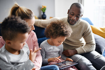 Multi ethnic family with two small children using tablet at home. - Powered by Adobe