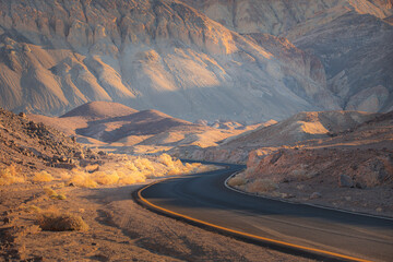 Dramatic golden light on an empty winding desert road through the rugged terrain of the badlands...