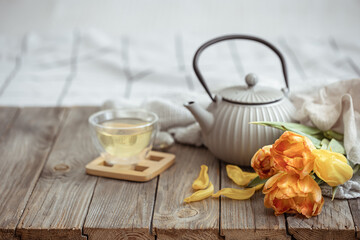Spring home composition with a cup of tea, a teapot and a bouquet of flowers on a wooden surface.