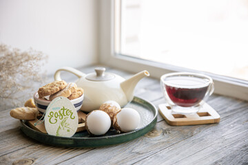 Easter composition with a cup of tea, teapot, cookies and Easter eggs.