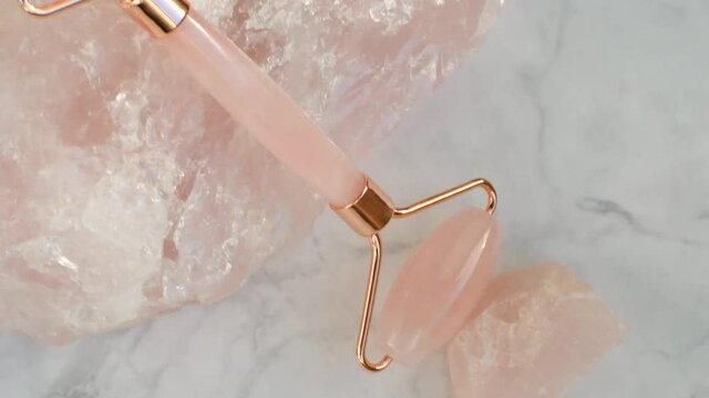 gua sha  rose quartz roller, rose quartz stones on gray marble background. face roller  on marble background, top view.Face massage tool.Skin care