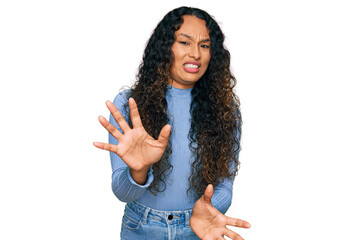 Young hispanic woman with curly hair wearing casual clothes disgusted expression, displeased and...