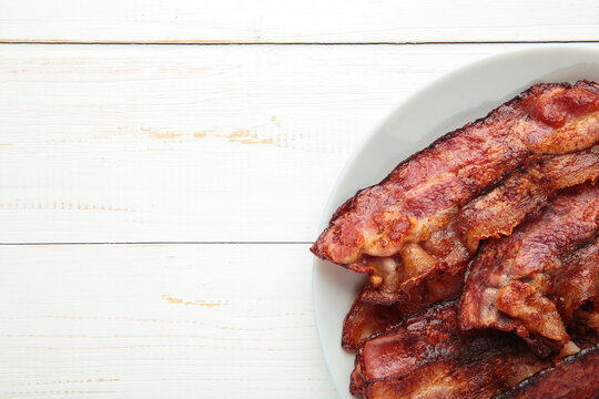 Fried bacon on white plate on light background