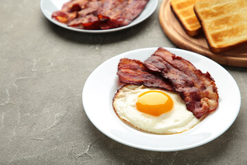 Eggs and bacon for breakfast on grey background. English breakfast with copy space.