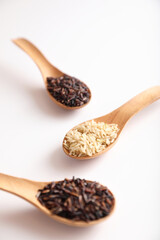 Organic raw brown rice and riceberry rice on spoon in close up