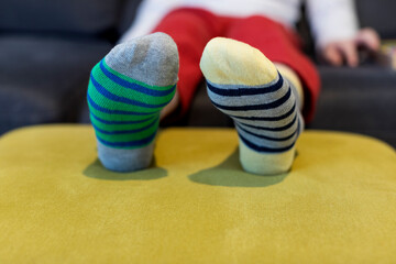 Down syndrome awareness concept. Boy wearing different socks while sitting on sofa at home....