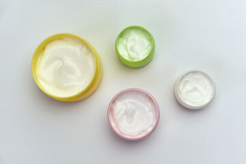 multi-colored jars with white cosmetic cream for face