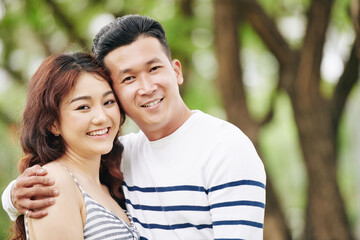 Portrait of happy hugging young Asian boyfriend and girlfriend smiling and looking at camera