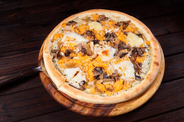 Pizza with cheese and mushrooms on a wooden plate. Close-up, selective focus