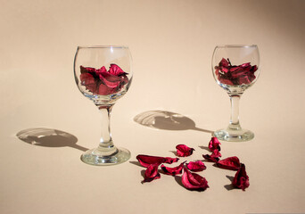 Wine glasses with red decoration or petals on table. Romantic minimal concept.