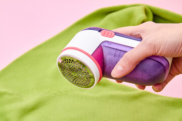 A wooman using Fabric shaver removes fabric pills from garments. Close-up, selective focus