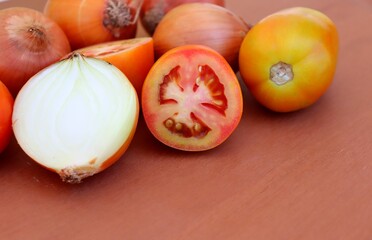 Tomatoes and onions on wooden background.