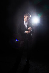 Portrait of an attractive young man in a black suit on a dark background with lighting in the studio