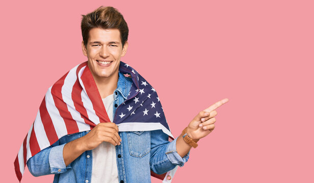 Handsome caucasian man holding united states flag smiling happy pointing with hand and finger to the side