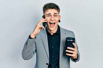 Young caucasian boy with ears dilation using smartphone and drinking a cup of coffee smiling and laughing hard out loud because funny crazy joke.