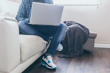 technology, home and lifestyle concept - close up of man working with laptop computer and sitting on sofa at home