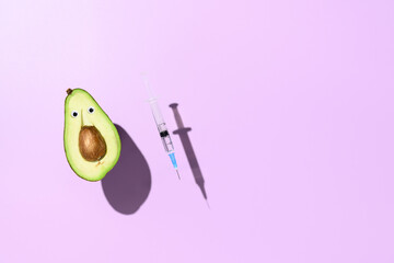 Concept of vaccination against coronavirus. Funny half an avocado and a syringe with vaccine...