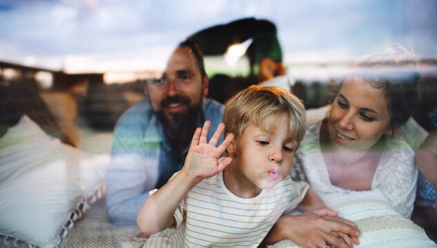 Small boy with parents by window, holiday in nature concept. Shot through glass.