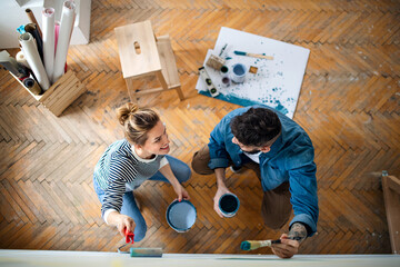 Top view of couple painting wall indoors at home, relocation and diy concept.