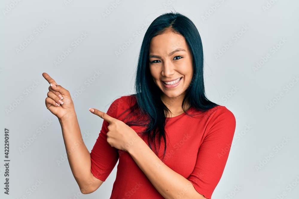 Wall mural beautiful hispanic woman wearing casual clothes smiling and looking at the camera pointing with two 