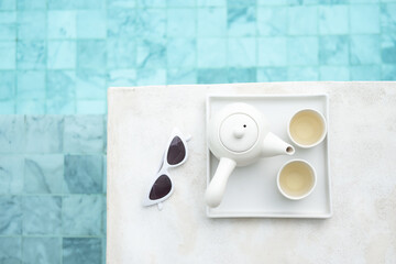 white sunglasses and hot tea pot near swimming pool in luxury hotel. Summer travel, vacation, holiday and weekend concept