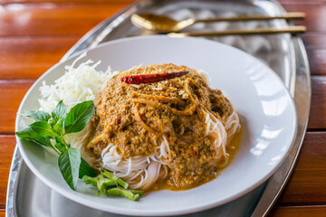 Thai Rice Noodles in Fish Curry Sauce with ingradient on wooden table