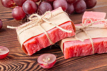Organic handmade soap scented with mulled wine on wood table. Sustainable and eco-friendly soap bar for body care wrapped in craft paper.